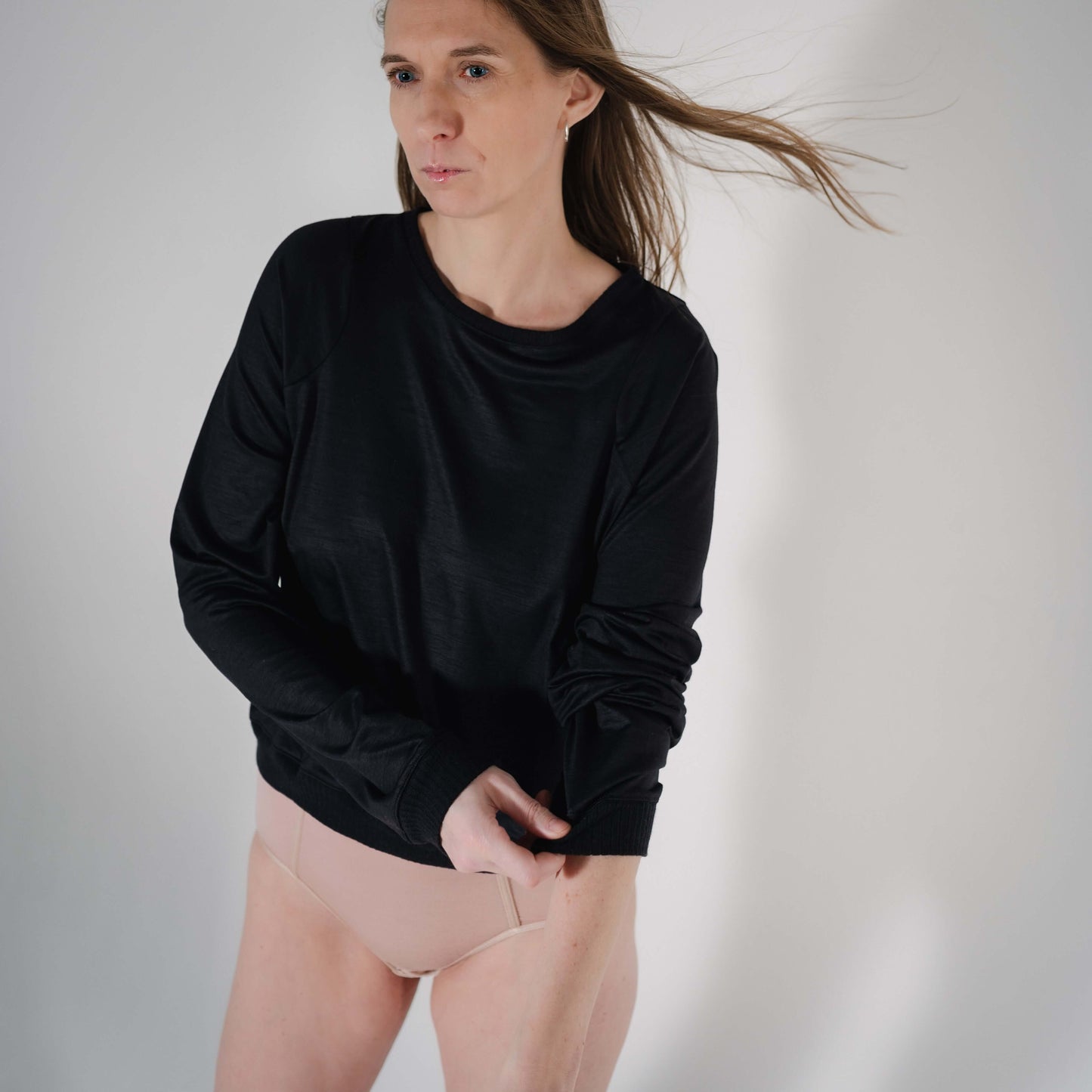 Stylish black wool sweater with loose sleeves and cozy fit, modeled by a tall woman.