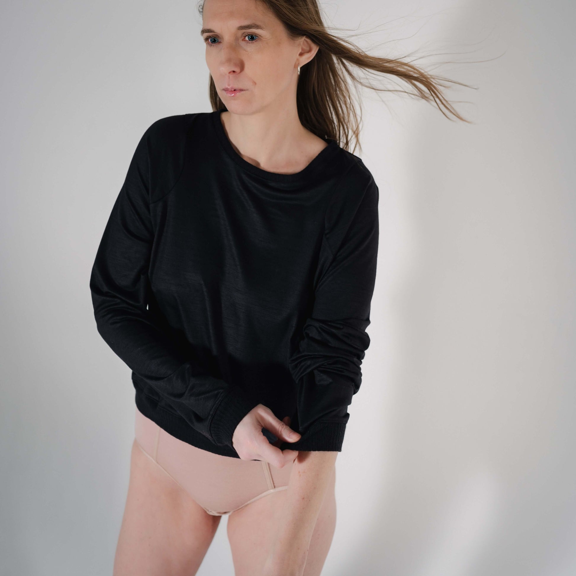 Stylish black wool sweater with loose sleeves and cozy fit, modeled by a tall woman.