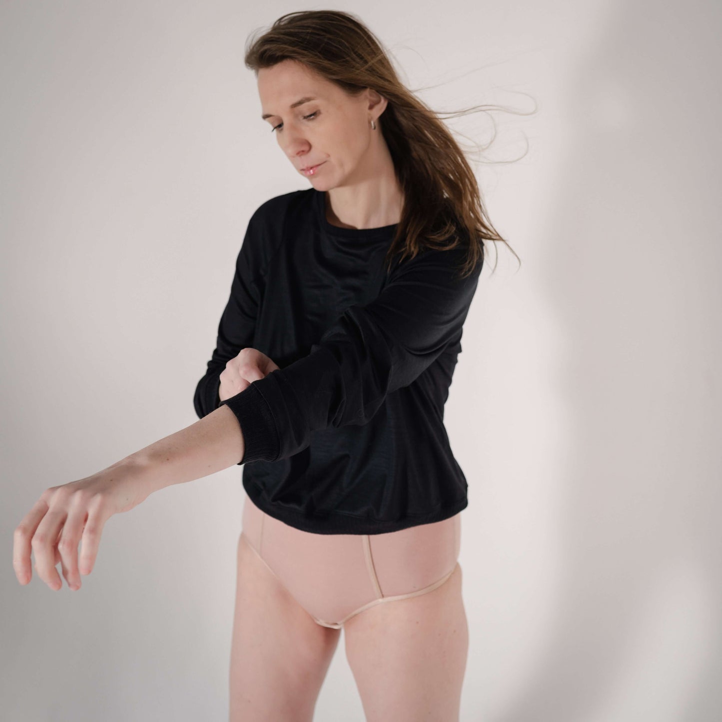 Model wearing a black long-sleeve top with loose sleeves, showcasing casual style and comfort.