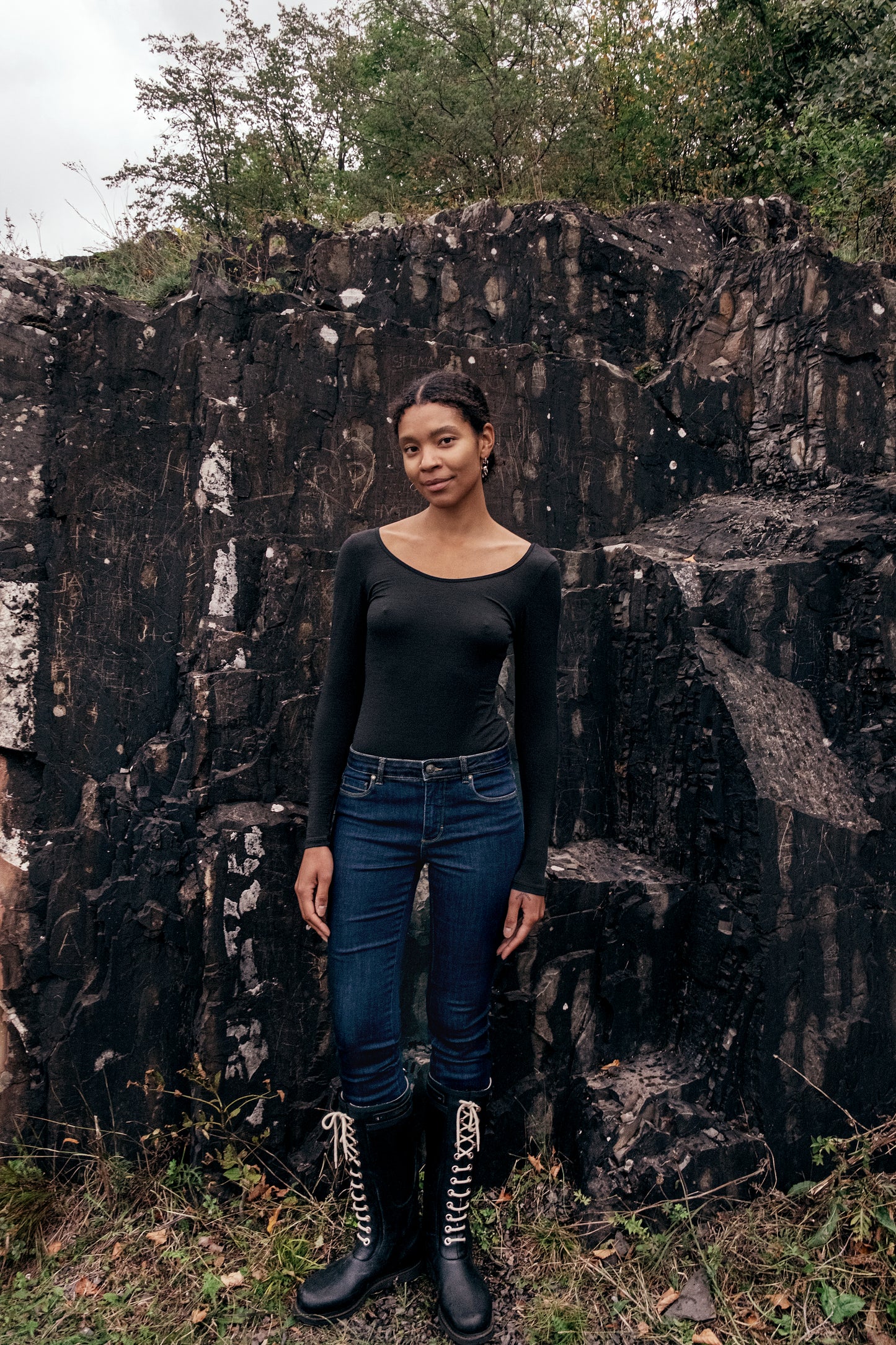 Model wearing Wełniane body Astra against a rocky background, showcasing elegant minimalism in fashion.
