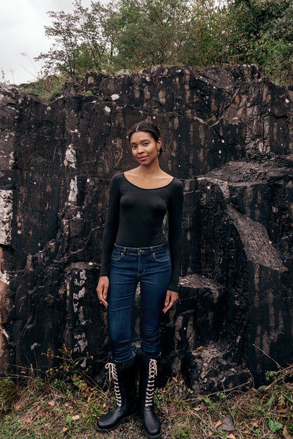 Model wearing Wełniane body Astra against a rocky background, showcasing elegant minimalism in fashion.