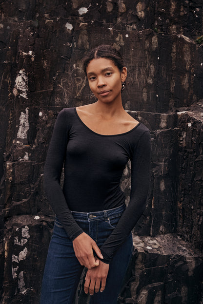 Model wearing Wełniane body Astra against a rocky background, showcasing elegant minimalism in fashion.