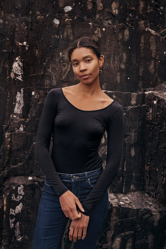 Model wearing Wełniane body Astra against a rocky background, showcasing elegant minimalism in fashion.