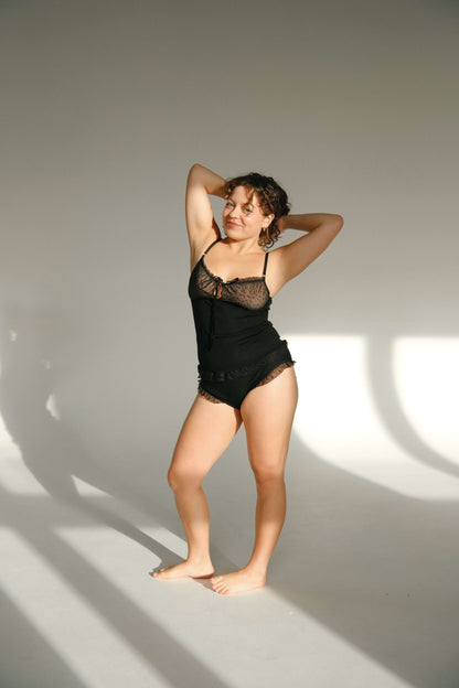 Model posing in a stylish black Merino wool and tulle top with ribbed weave and star-patterned tulle.